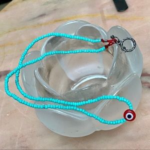 Turquoise beaded necklace with red evil eye.
